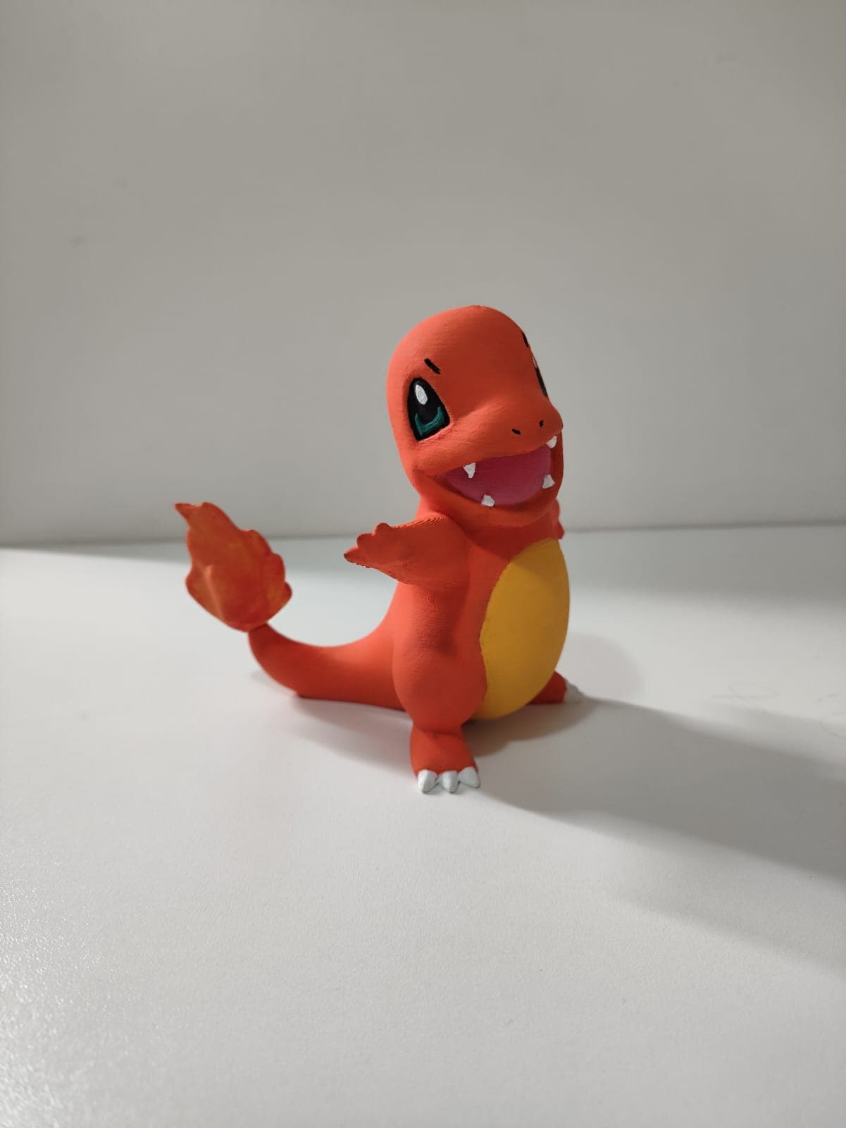 Figura do Charmander em plástico laranja pintada, pose alegre com braços abertos sobre fundo branco.