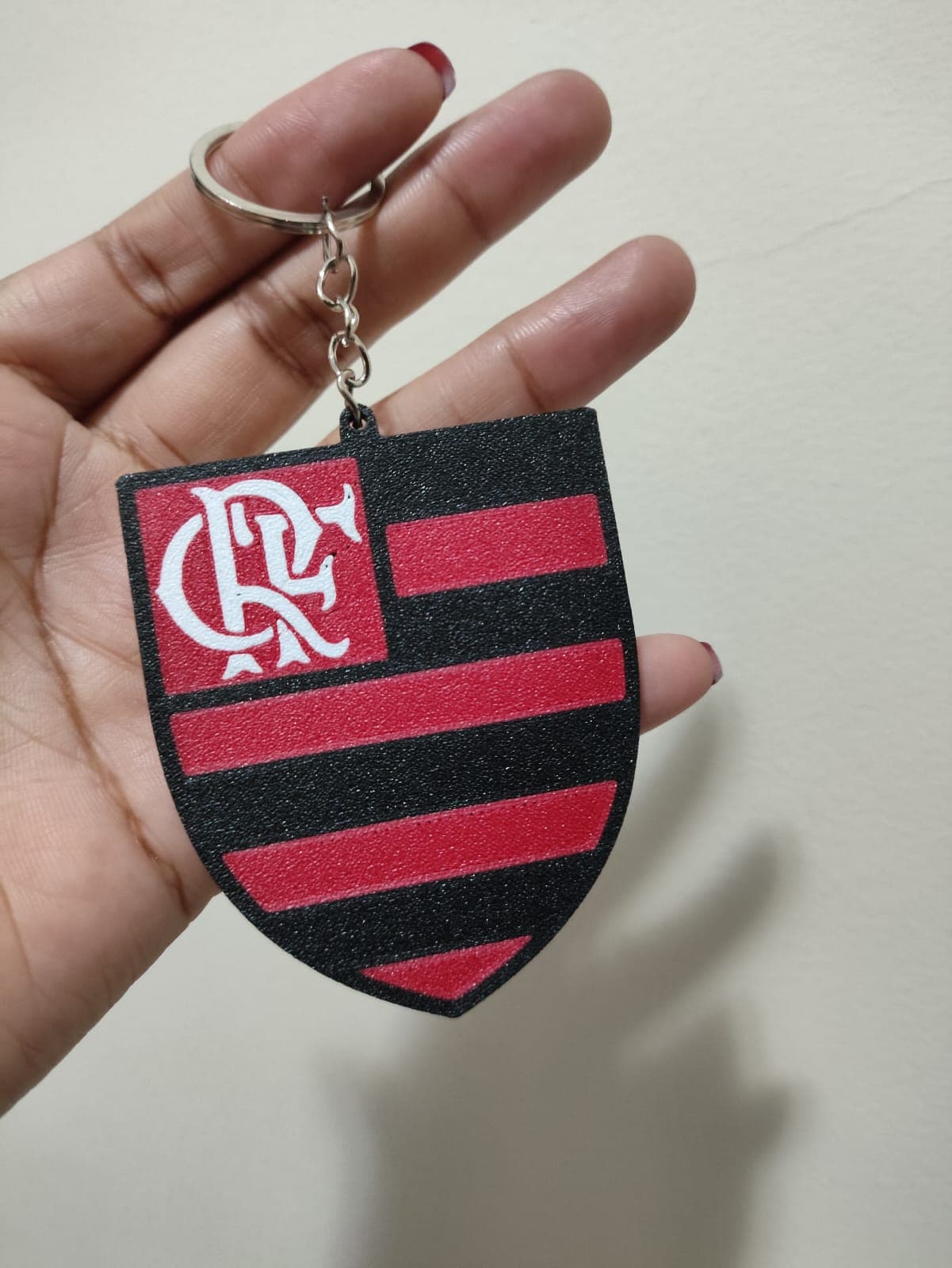 Chaveiro em formato de escudo do Flamengo com listras e monograma CRF, textura fosca.