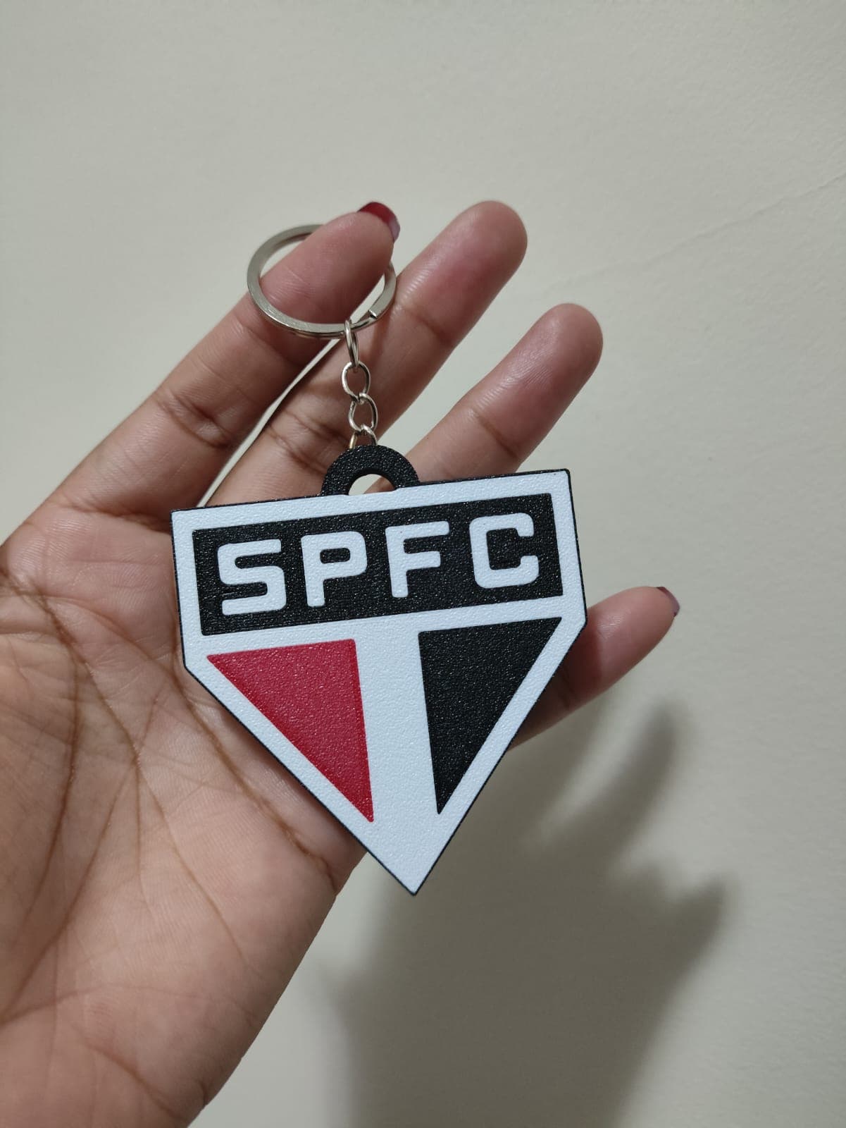 Chaveiro com escudo do São Paulo FC em vermelho, preto e branco, acabamento texturizado.