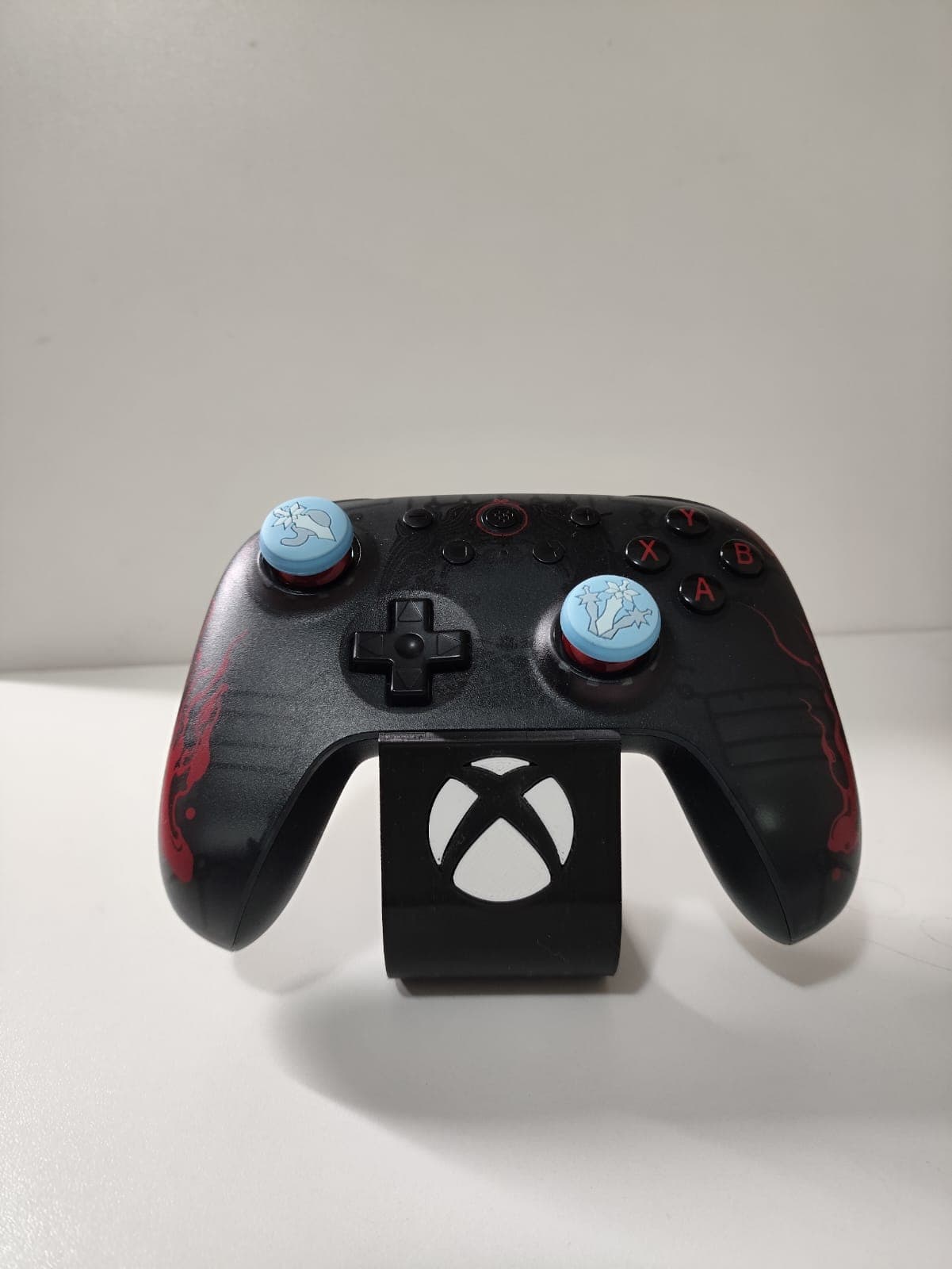 Controle preto e vermelho em suporte vertical sobre mesa de madeira.